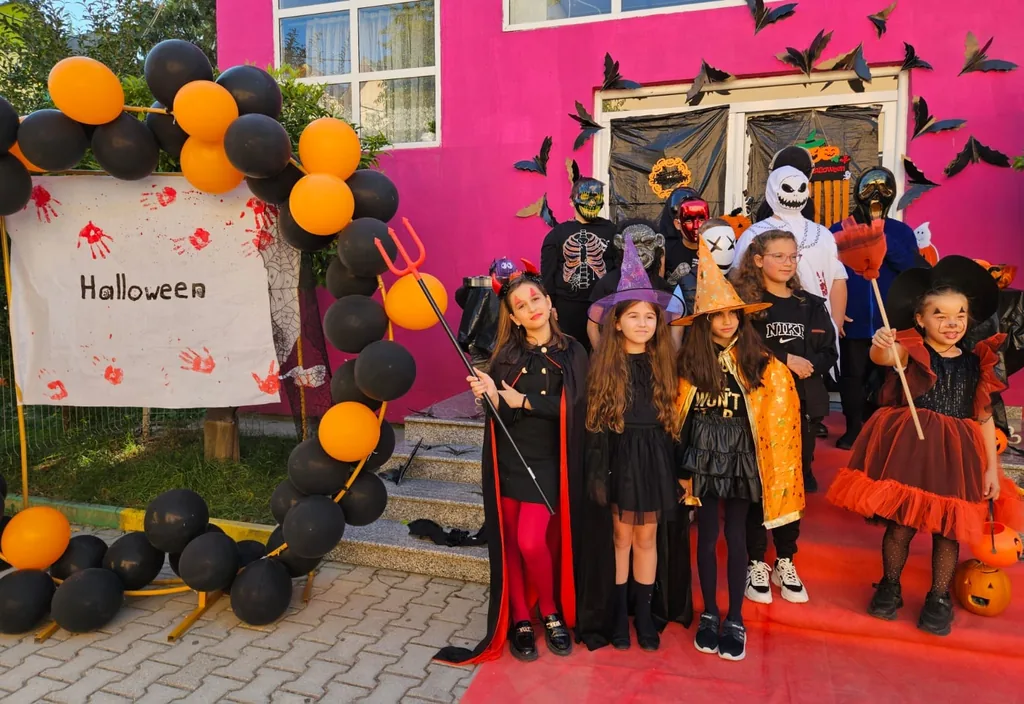 Nxënës me kostume pranë dekorimeve të Halloween